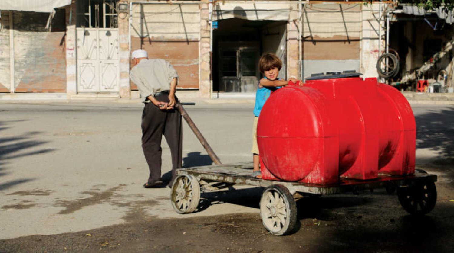 رجل مسن يجر عربة متنقلة لتعبئة مياه الشرب في جرمانا – إنترنت